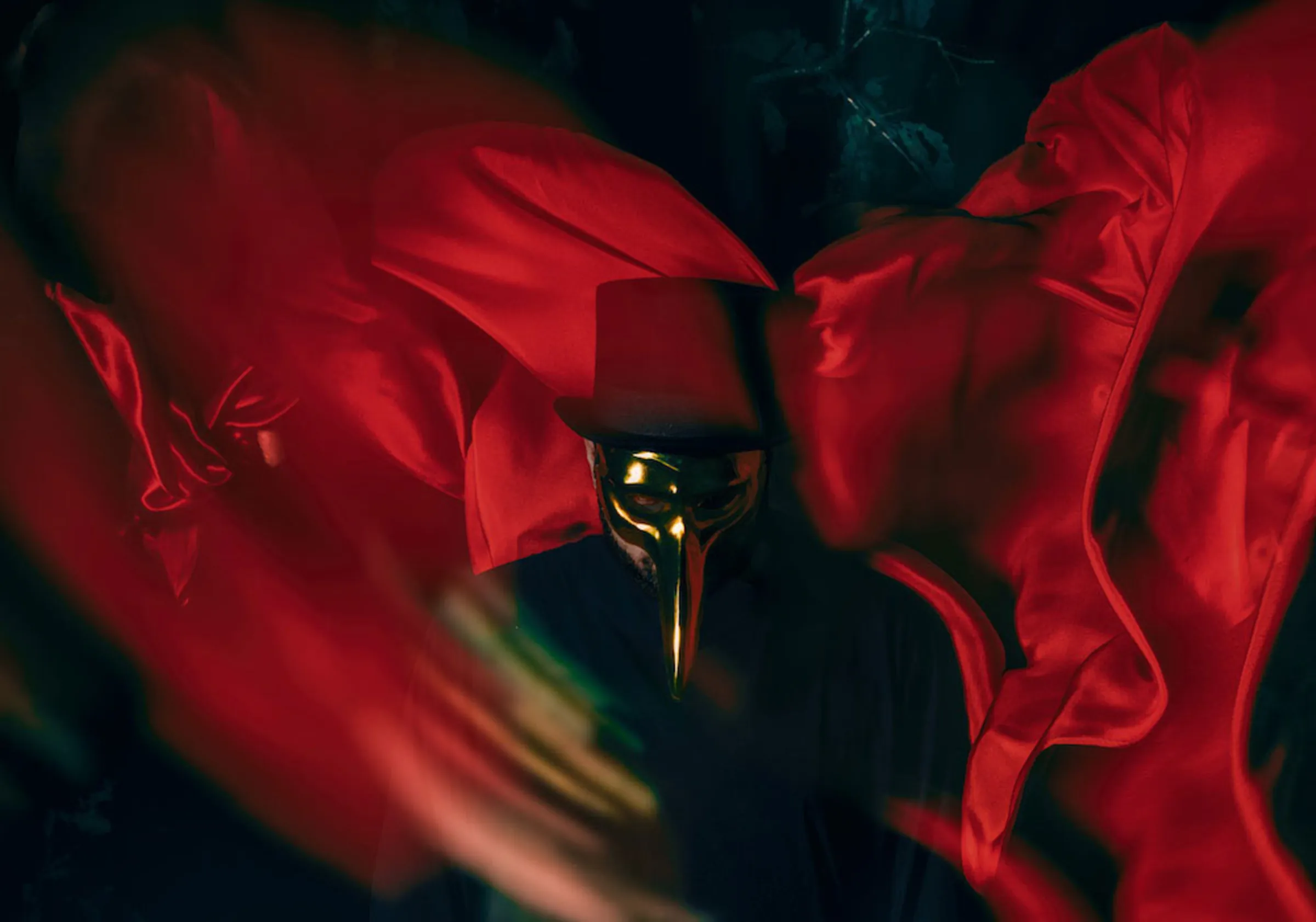 Claptone in a billowing red cloak against a dark sky