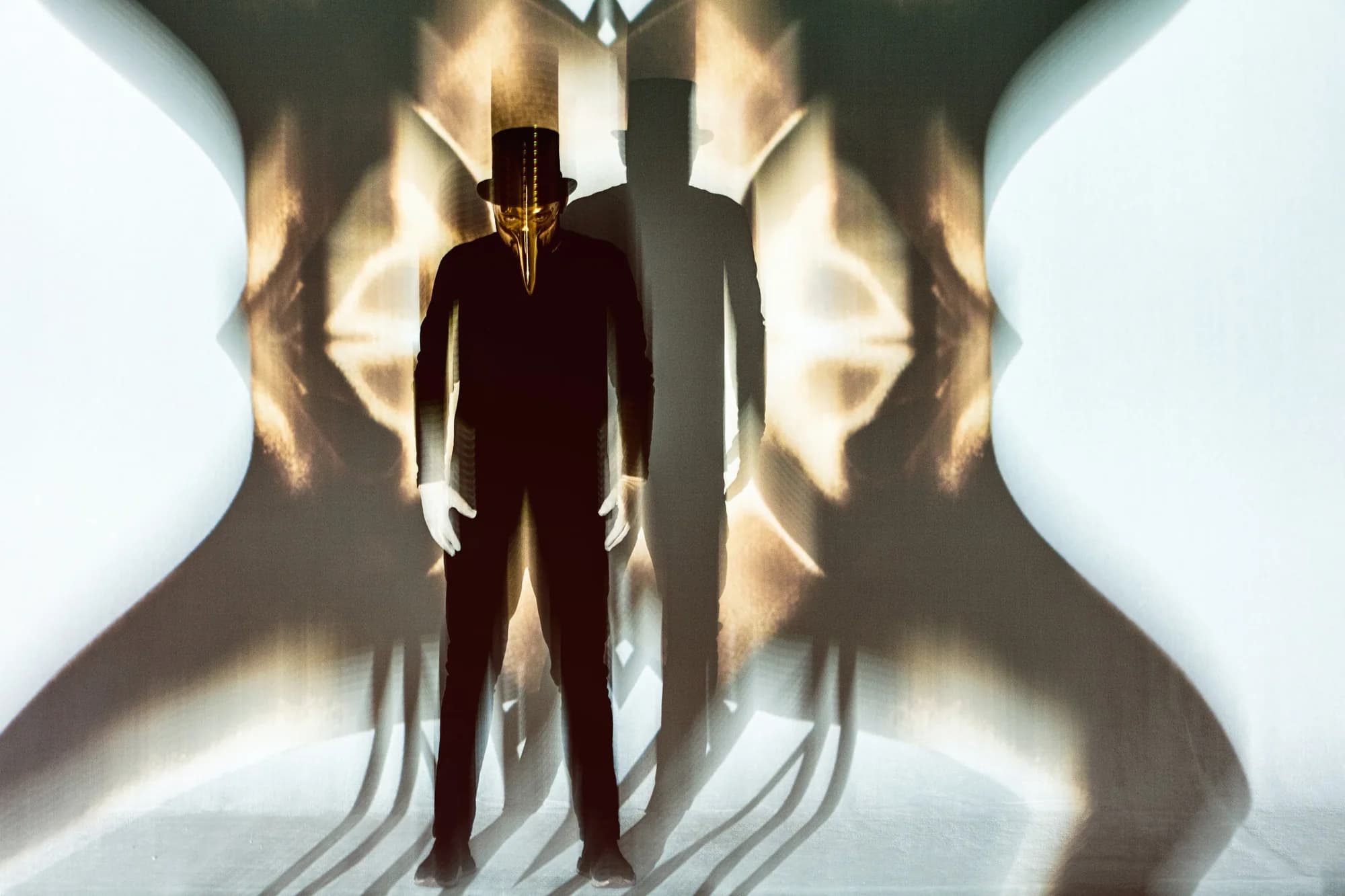 Claptone in silhouette between two glowing white light installations