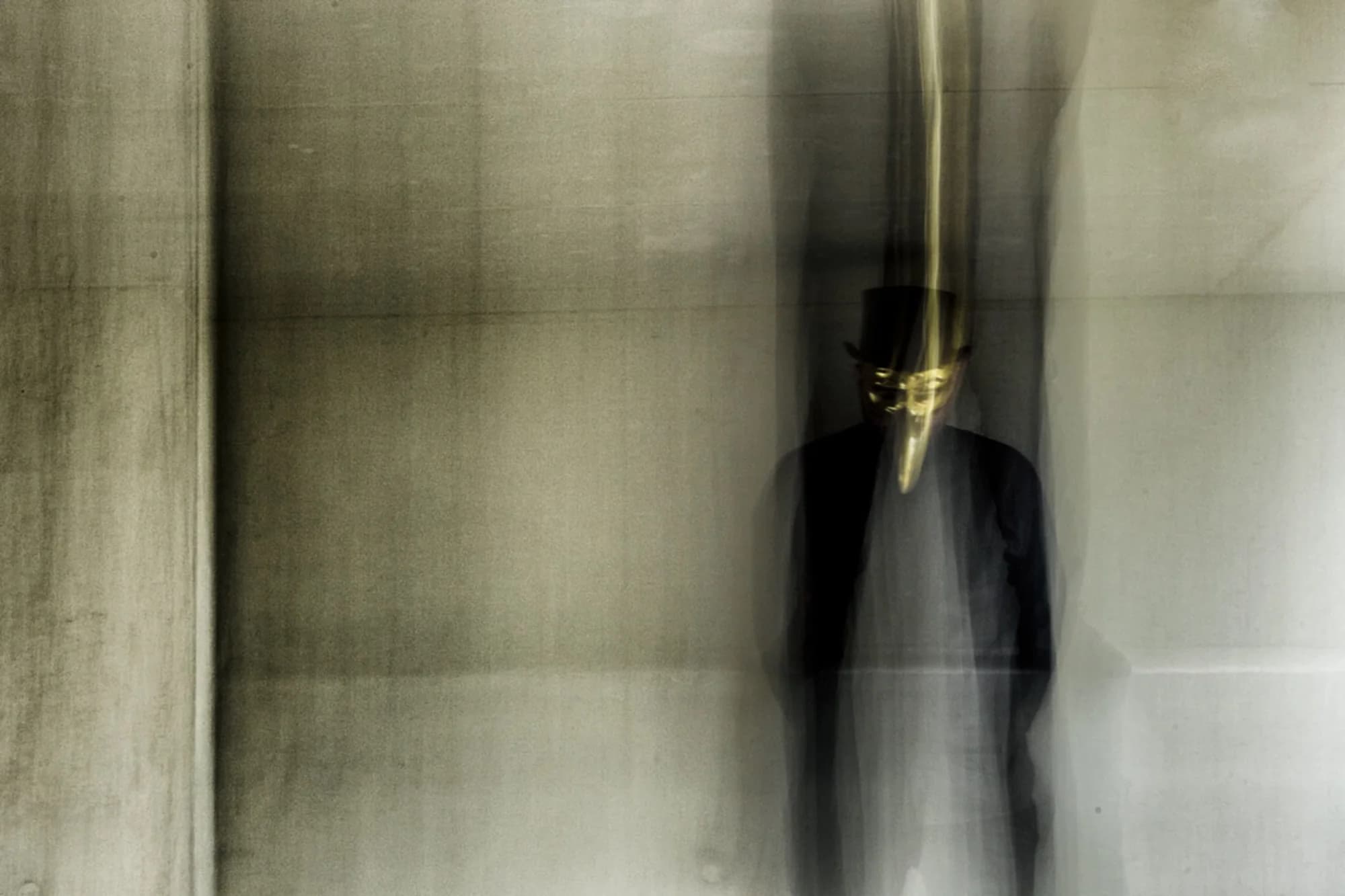 A ghostly long exposure of Claptone in a pale concrete space