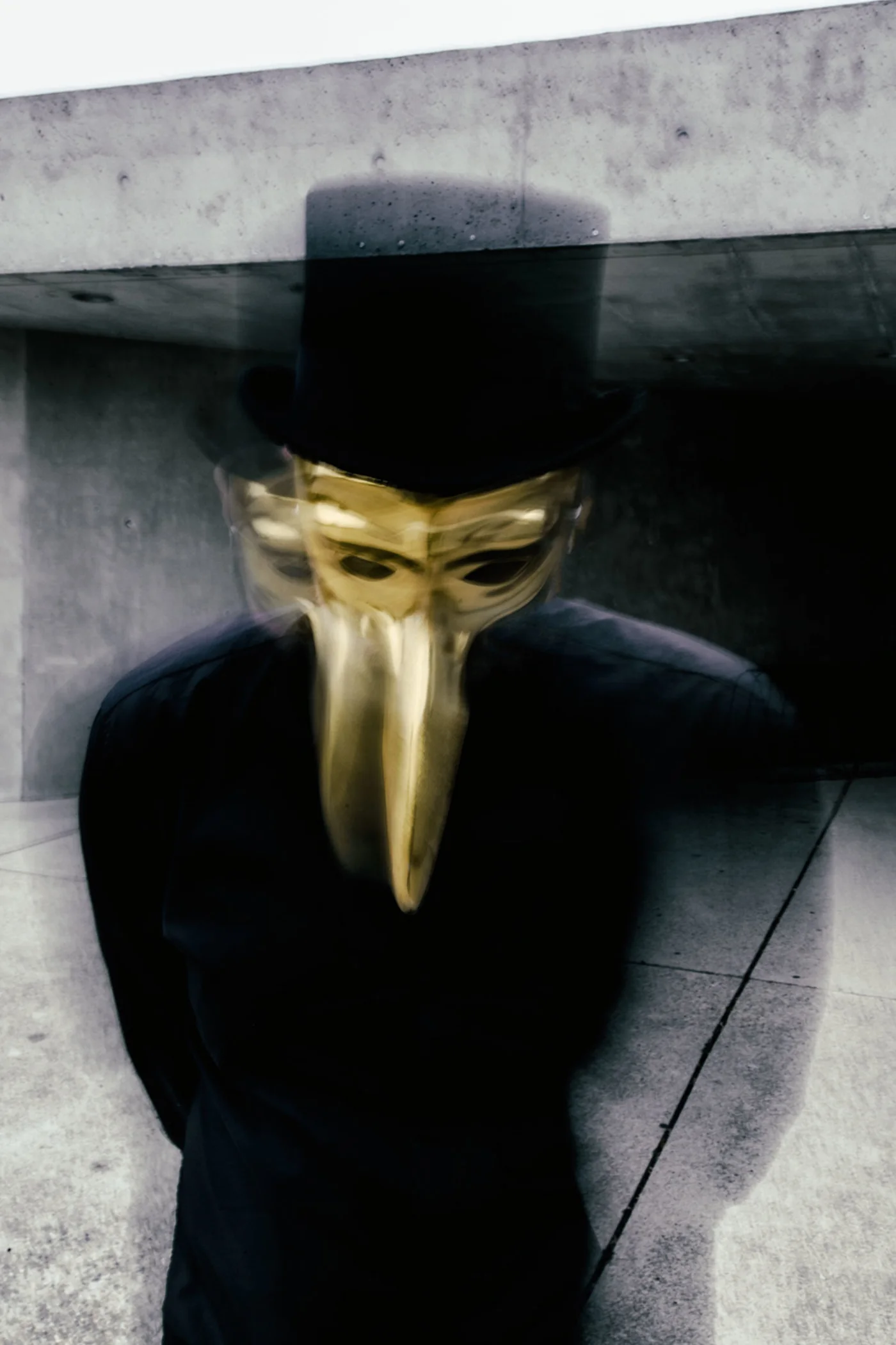 Claptone in a top hat and golden beak beneath a concrete overhang