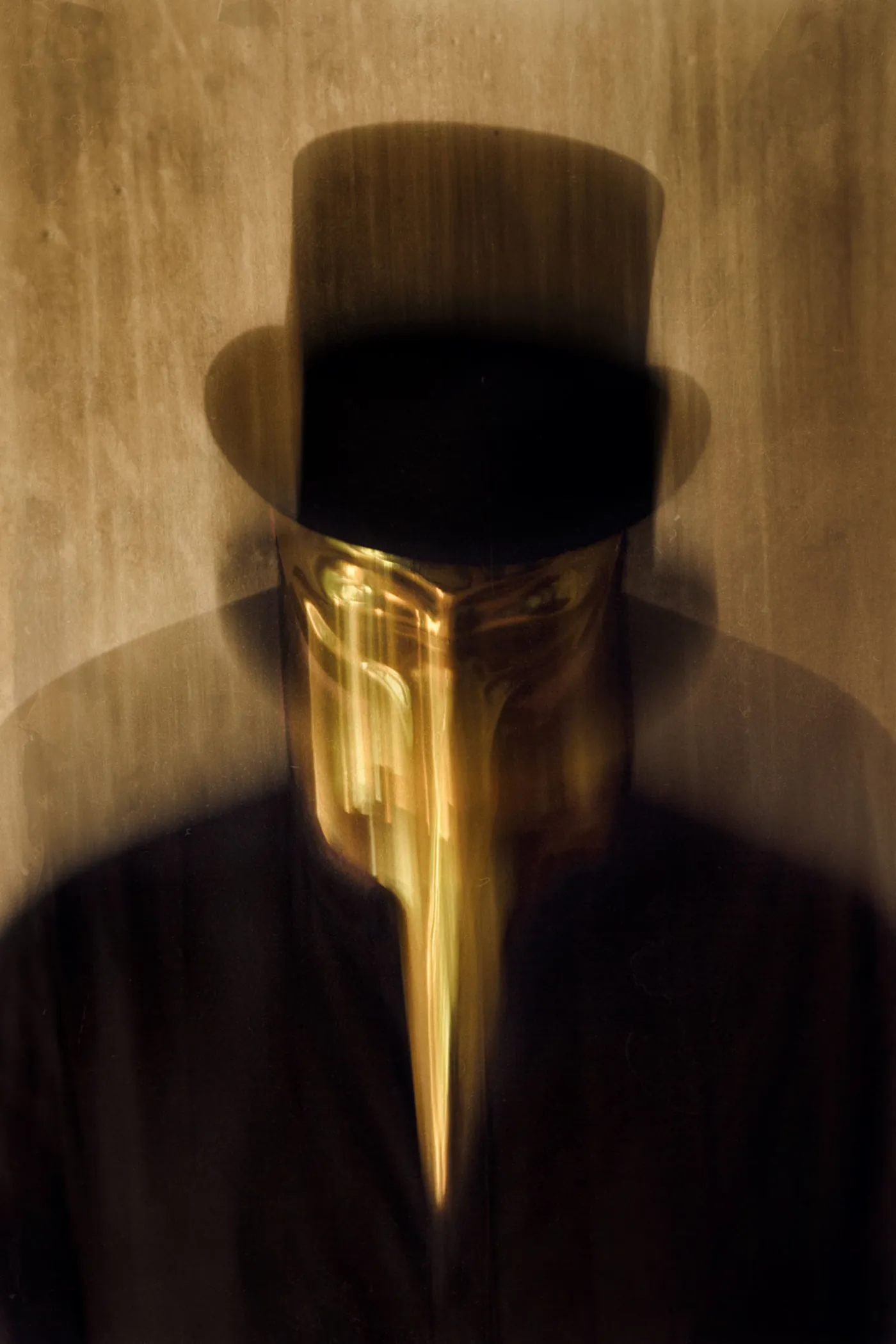 Claptone in the golden mask and a top hat against a weathered gold wall